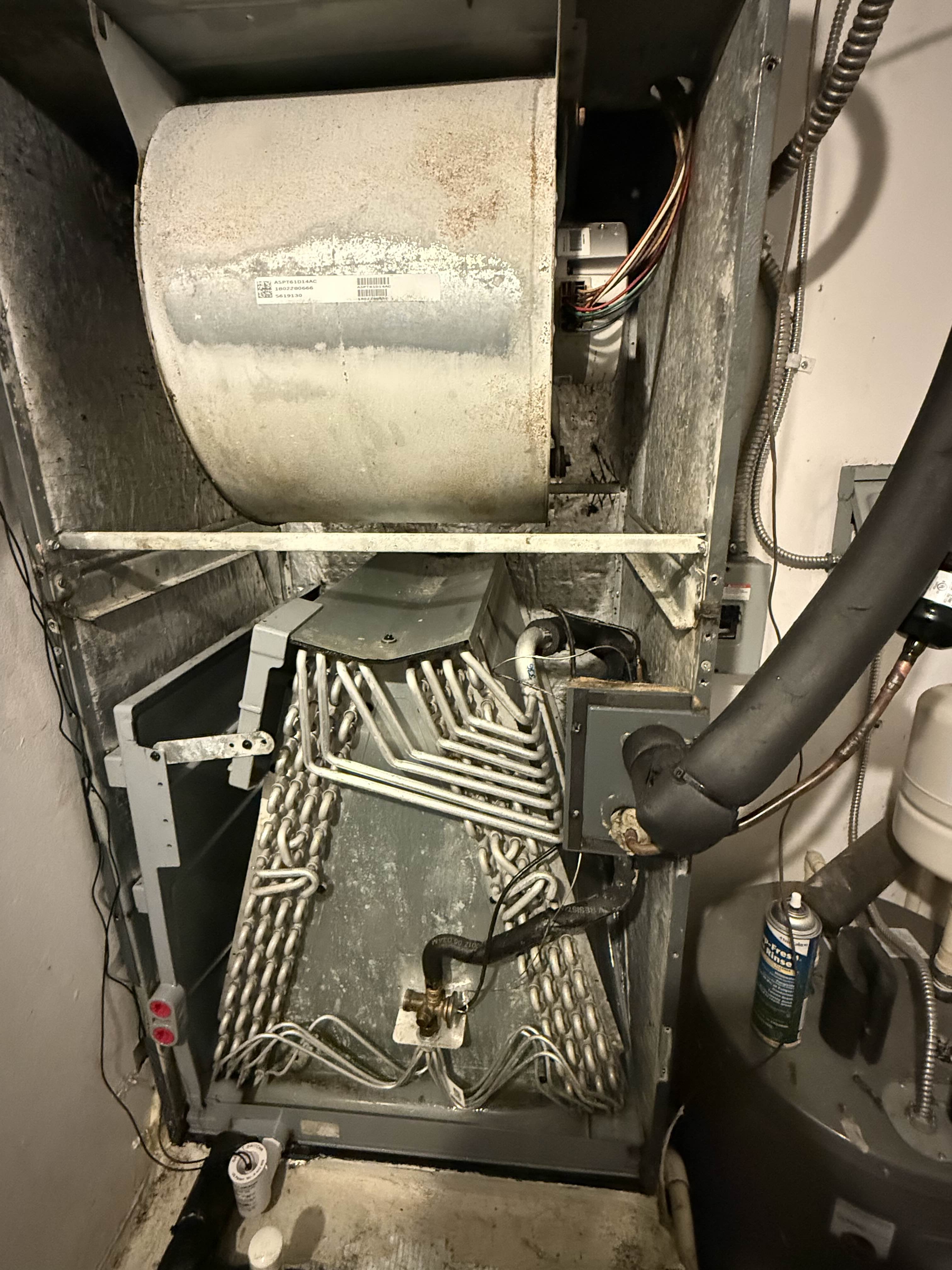 Open air handler showing blower, evaporator coil, drain pan, PVC condensate drain line, and inline float switch